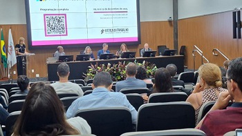 Foto do auditório mostra público e a mesa de honra