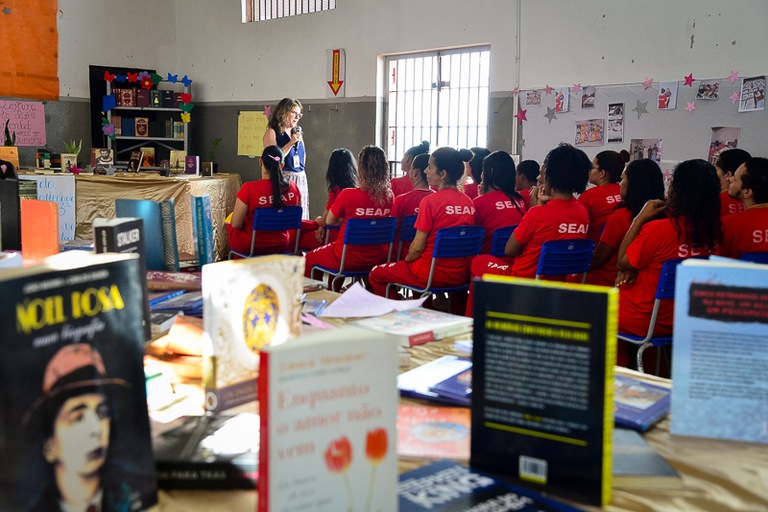 Psicóloga palestra para detentas em ambiente cercado por livros 