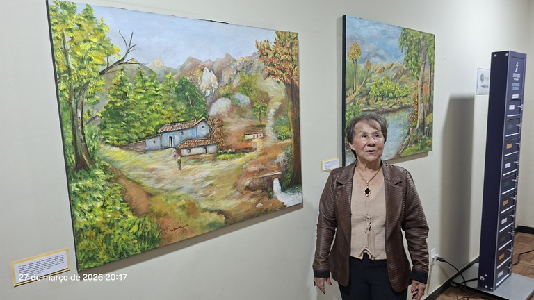 Pintora Helena Alves de Oliveira apresenta um dos seus quadros expostos na Exposição Crisálida