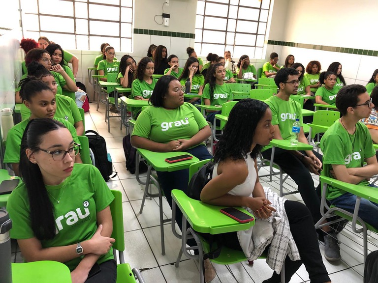 foto dos alunos sentados de uniforme verde nas carteiras