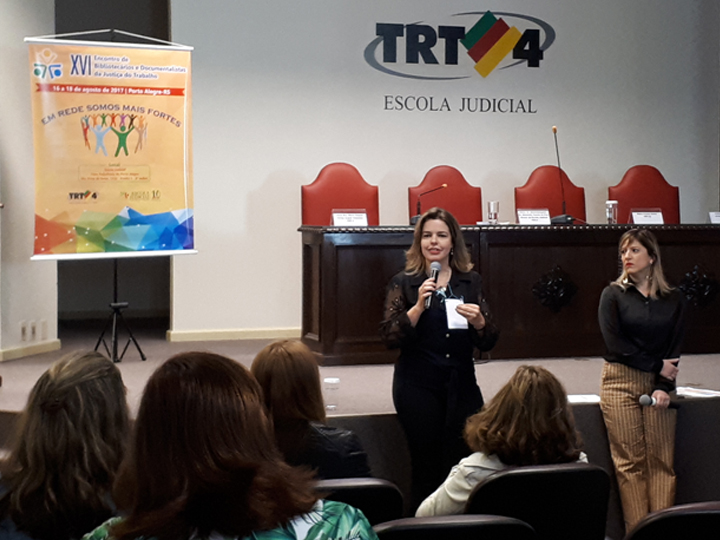 A juíza Maria Raquel Ferraz ministra palestra sobre a revista do TRT-MG junto com a servidora Isabela Márcia de Alcântara.  