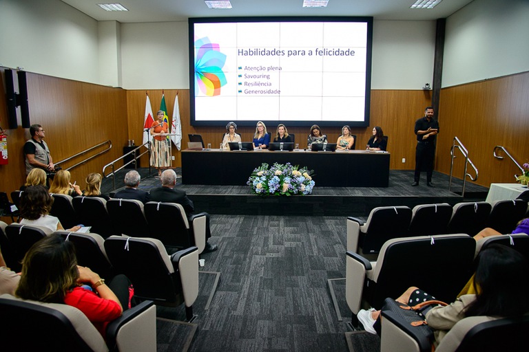 foto da mesa de honra com juízas, servidoras, desembargadoras e palestrante, além de parte da plateia