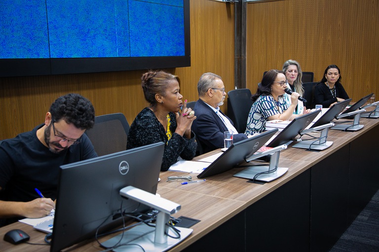 foto da juíza Adriana Campos de Souza Freire Pimenta falando no microfone sentada na mesa de honra