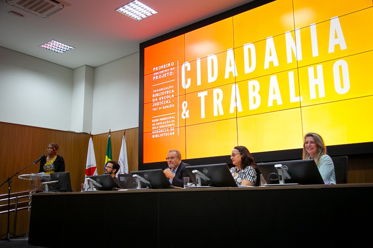 foto da bibliotecária chefe Márcia Pimenta em pé no púlpito falando ao lado da mesa de honra 