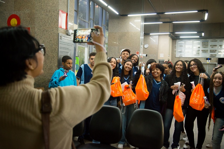 Professora tira foto dos alunos segurando os kits de aprendizagem.