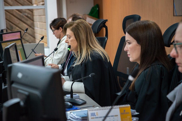foto de presidente do TRT-MG, desembargadora Denise Alves, falando no microfone ao lado de servidora e demais autoridades