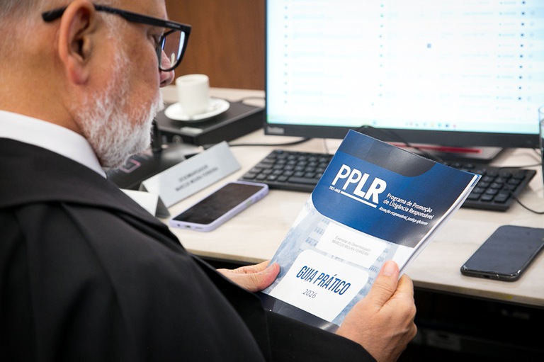 2026 0312 Pleno-34.jpg foto de desembargador conferindo o guia prático do PPLR impresso em suas mãos