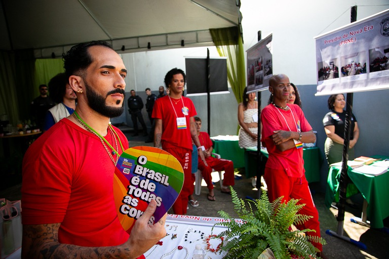 foto de internos e internas de uniforme vermelho prestando atenção no evento 
