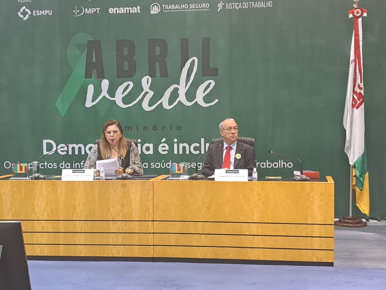 foto do desembargador Sebastião Geraldo sentado na mesa do Seminário do TST ao lado de palestrante