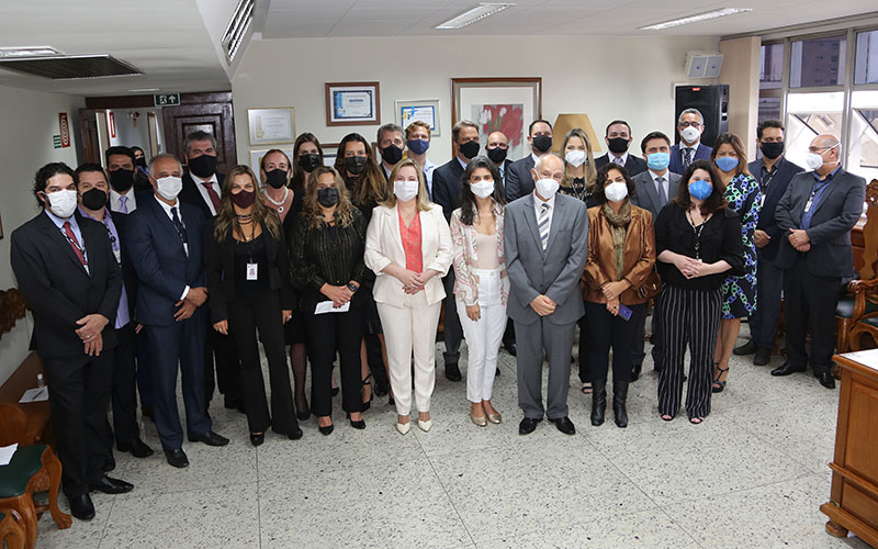 Foto de todos os gestores empossados com o presidente do TRT-MG e do juiz auxiliar da presidência. Ao fundo, uma parede com vários quadros.