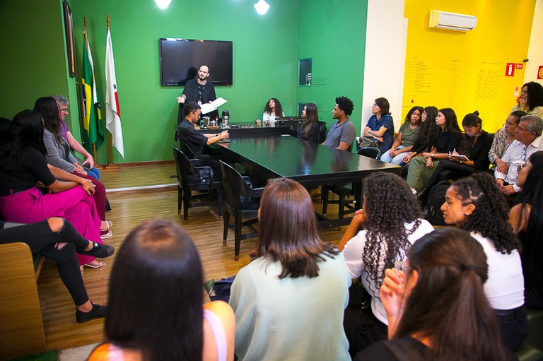 Estudantes assentados na sala de audiência da Exposição Trabalho e Justiça e o juiz Vitor Pombo ao centro, presidindo a audiência