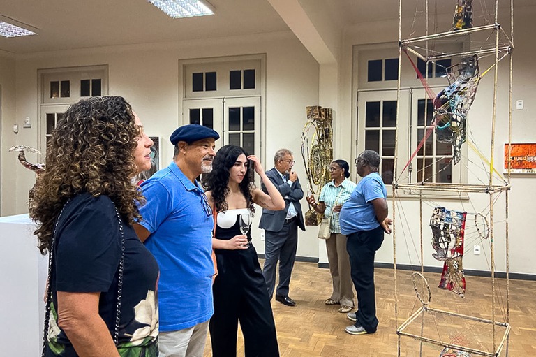 foto de visitantes em pé juntos apreciando obras do artista