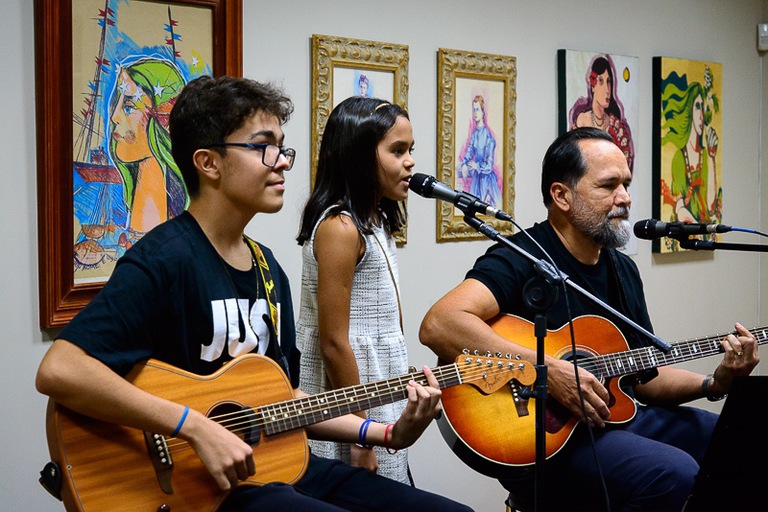 foto do presidente do TRE ao lado dos filhos tocando violão e cantando 