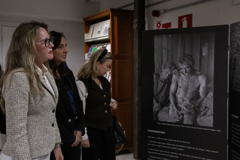 foto da desembargadora Paula Cantelli visitando a exposição de fotos junto com demais convidados.