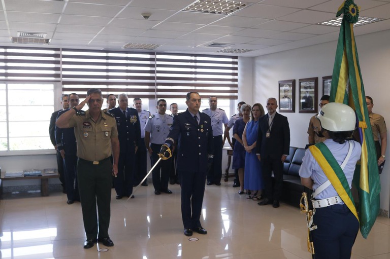 foto de militares fazendo a troca de comando, um deles segura uma espada e convidados estão atrás 