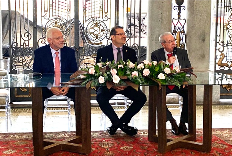 WhatsApp Image 2025-12-15 at 15.42.01.jpeg foto do desembargador Sebastião de Oliveira sentado na mesa de honra ao lado de duas autoridades.