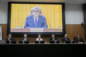Mesa de honra do TRT-MG com um telão ao fundo com a imagem do ministro do TST