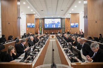 Foto do Pleno mostra os desembargadores dipostos em seus lugares; ao fundo, a mesa presidida pelo desembargador Sebastião Geraldo e, acima, telão com participação telepresencial