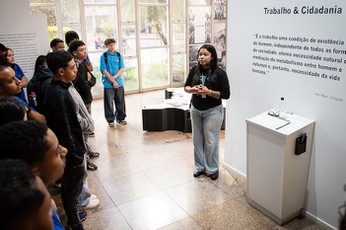 foto de monitora explicando para alunos na exposição Trabalho e Cidadania