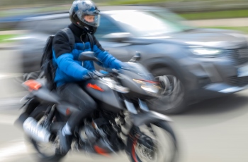 Foto de um motociclista se movimentando em grande velocidade no meio do trânsito.