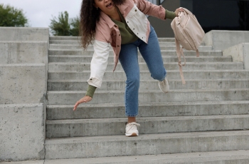 Foto de mulher com mochila tropeçando na escadaria.