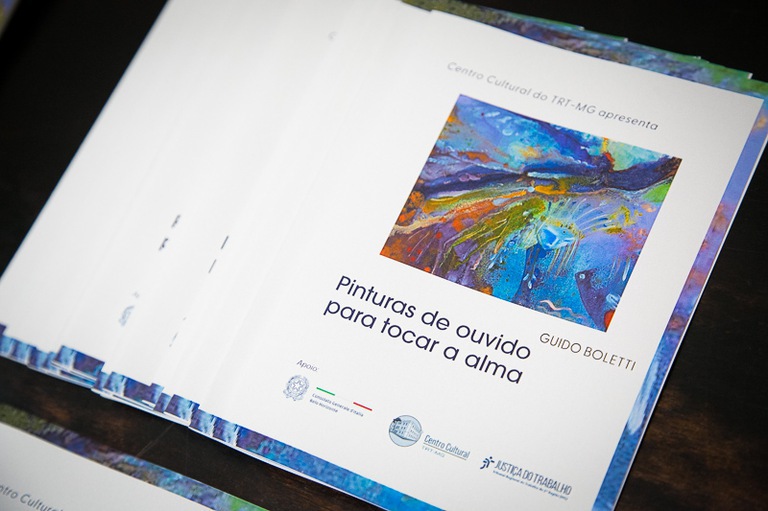 Catálogos com as obras do artista Guido Boletti da exposição "Pinturas de Ouvido para Tocar a Alma"