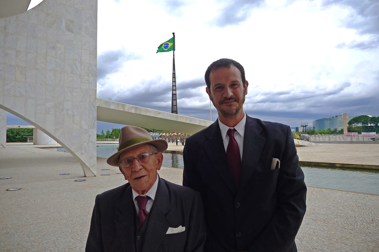 A imagem representa uma fotografia tirada em 2013, do curador da exposição Guilherme Horta junto ao fotográfo Assis Horta, no Palácio do Planalto.