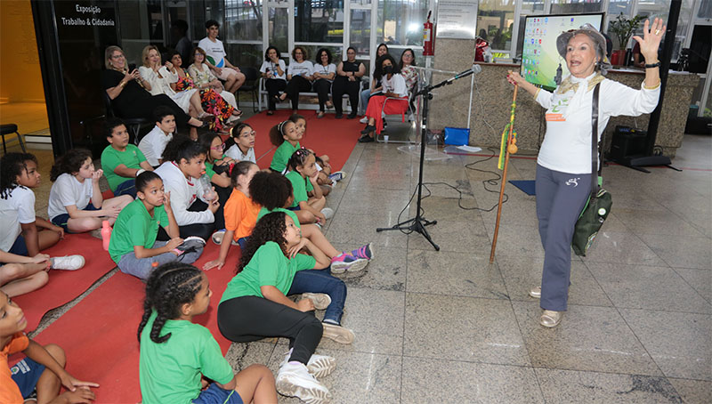 A escritora Diva Dorothy durante contação de história para as crianças; ao fundo, magistrados e servidores que atuam no PCTIEA e no Centro de Memória e professores da Escola Municipal Honorina de Barros